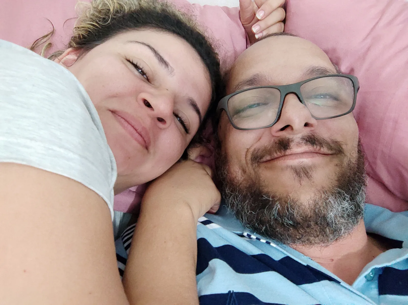 Juliana e Lucas deitados lado a lado, rostos juntos no travesseiro